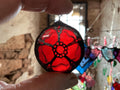 Hand holding a red and black red rose of Lancaster stained glass ornament with a blurred background