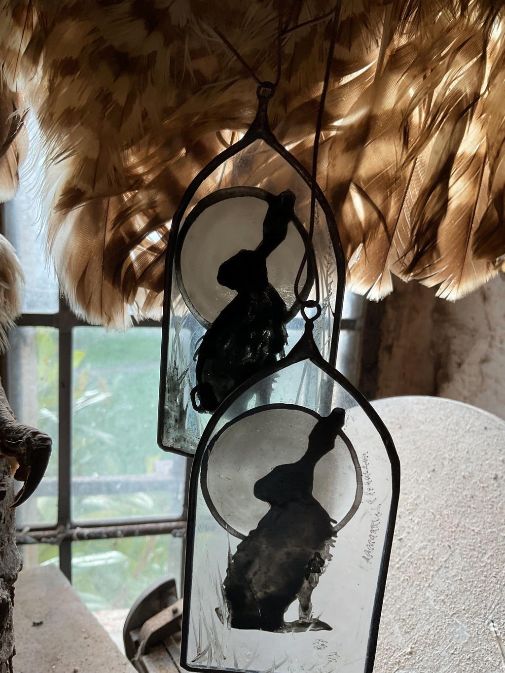 Decorative hangings with silhouettes of a jack rabbit  against a moonlit sky, surrounded by feathers.