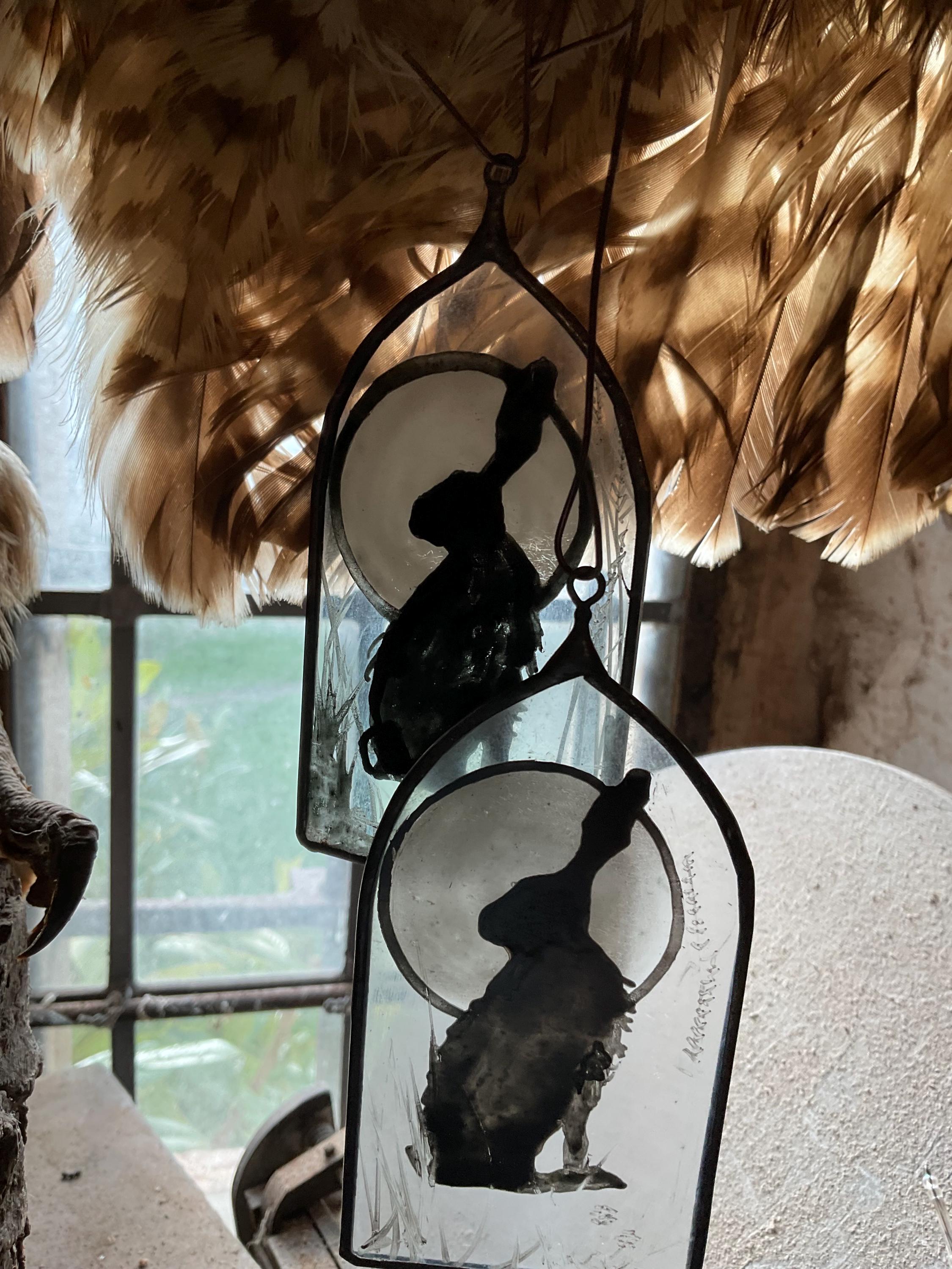 Decorative hangings with silhouettes of a jack rabbit  against a moonlit sky, surrounded by feathers.
