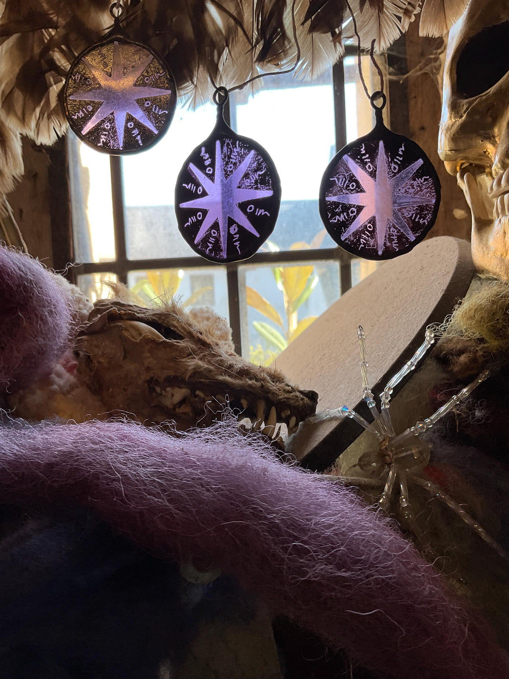 Decorative purple and black circular stained glass decors with star patterns hanging near a window.