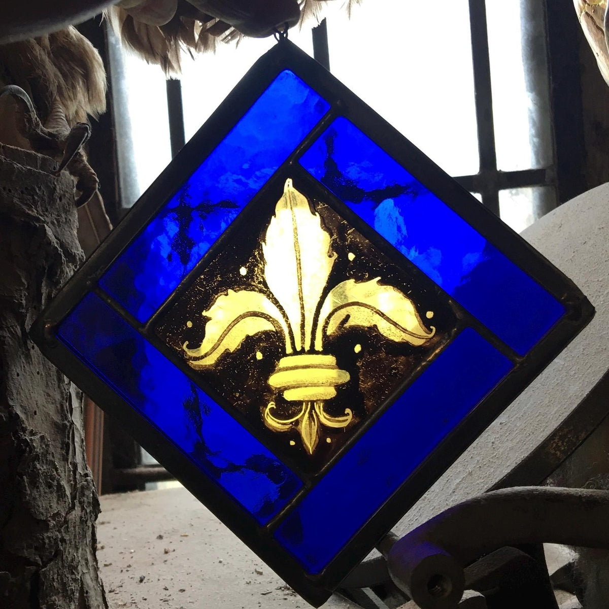 Stained glass panel with gold fleur-de-lis design on a blue background