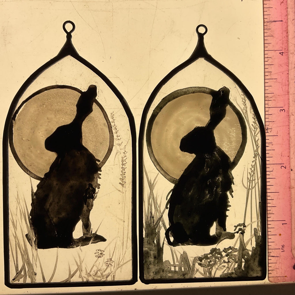 Two black silhouettes of animals in a decorative frame with a ruler for scale.