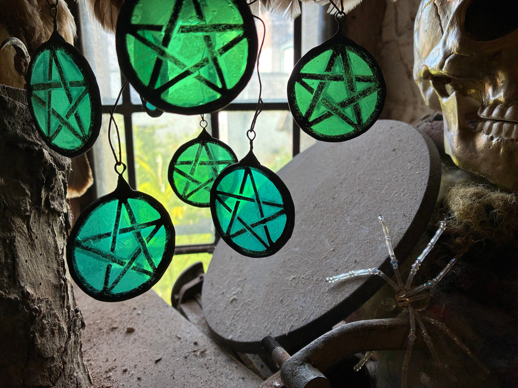 Decorative green and turquoise light catchers hanging against a leaded window.