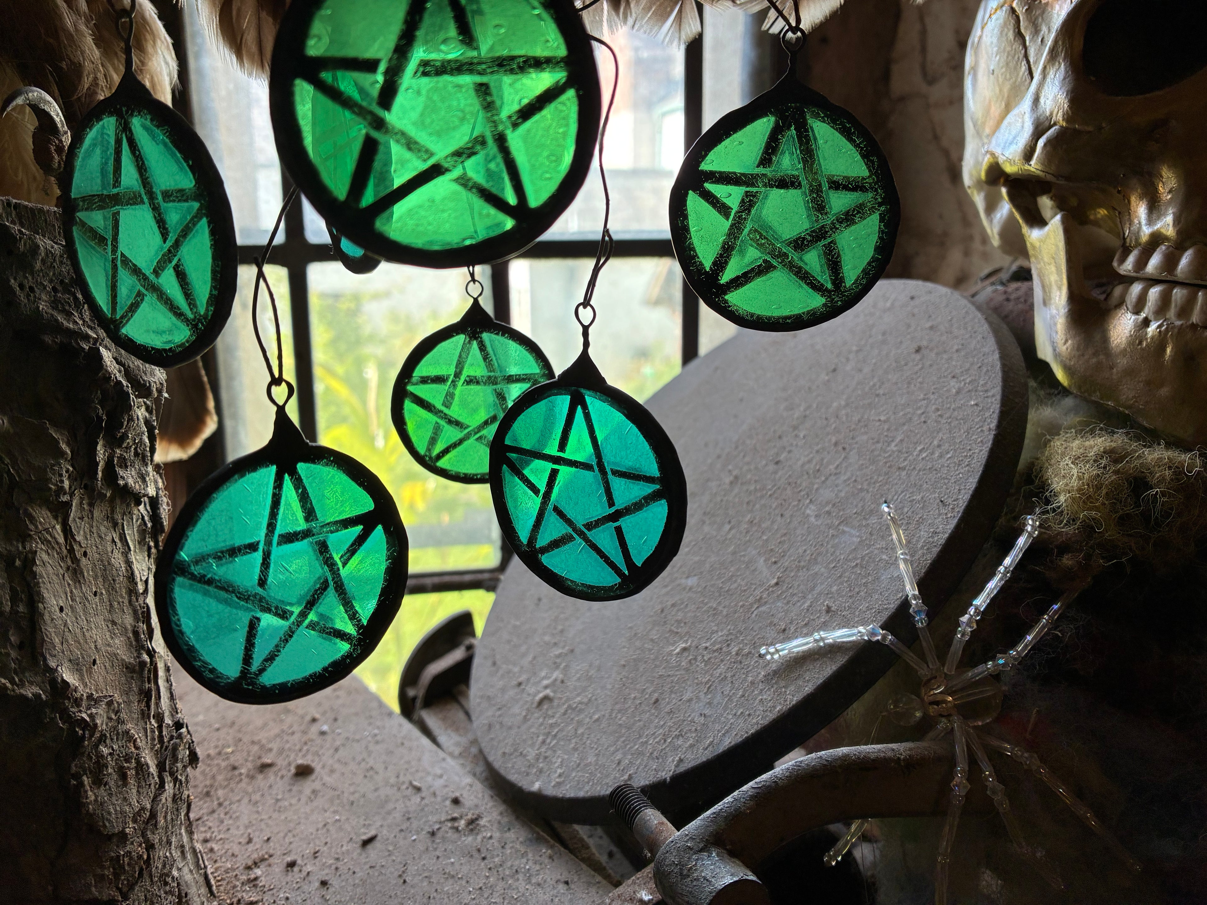 Decorative green and turquoise light catchers hanging against a leaded window.