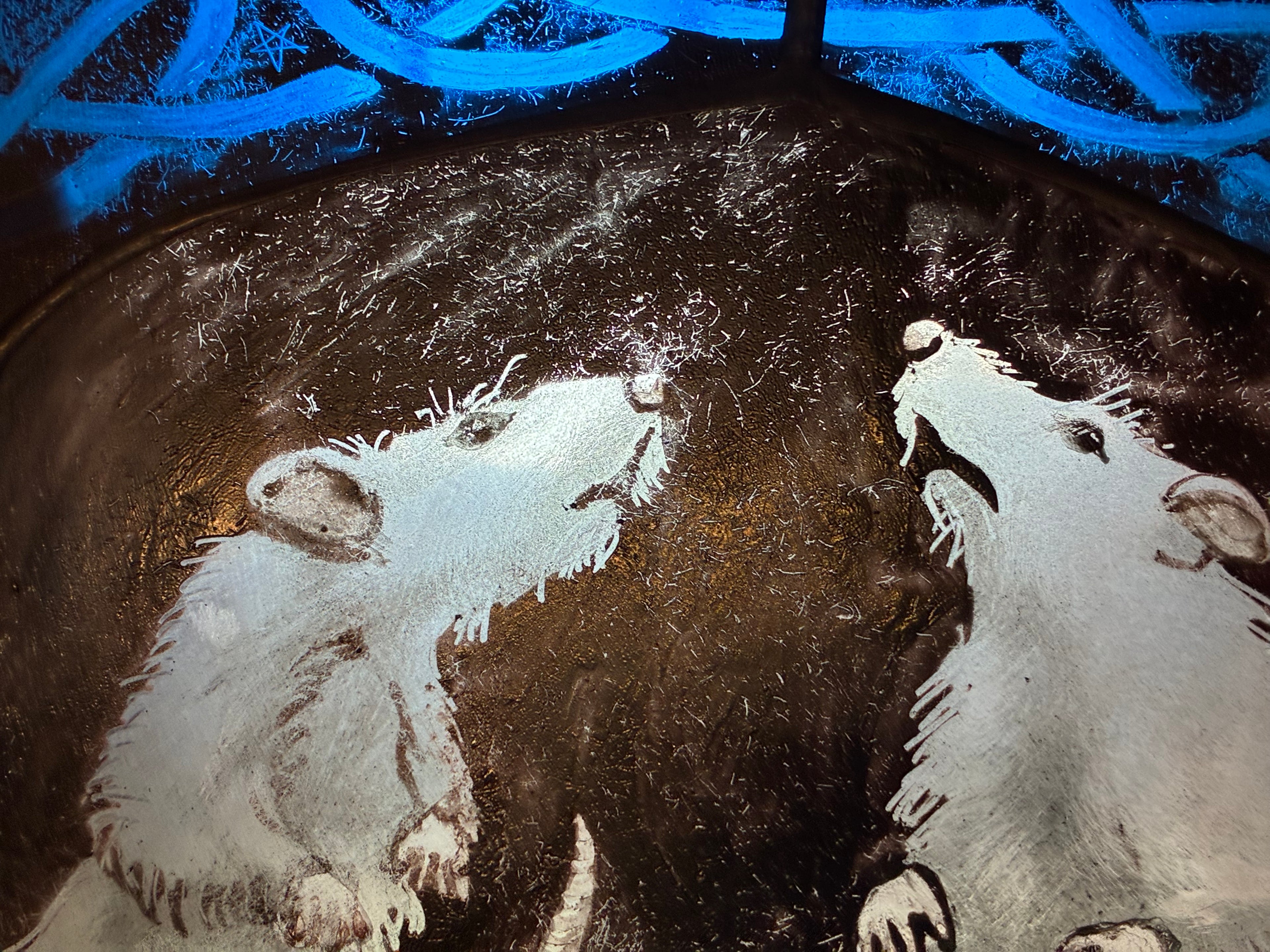 A close-up of a dark textured surface featuring a white painted illustration of two rats facing each other, with bright blue abstract curved lines across the top.