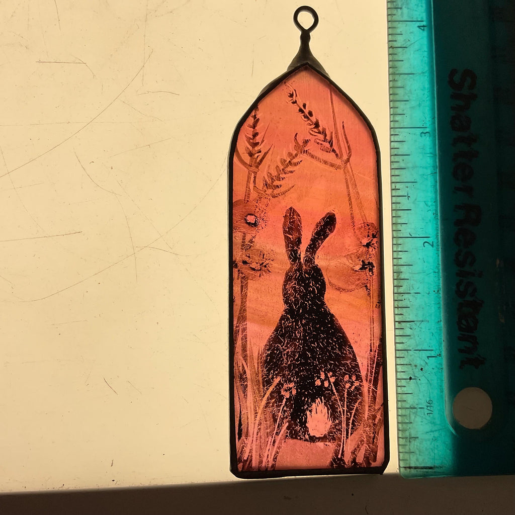 Decorative glass panel with a rabbit silhouette and plants, next to a ruler for scale.