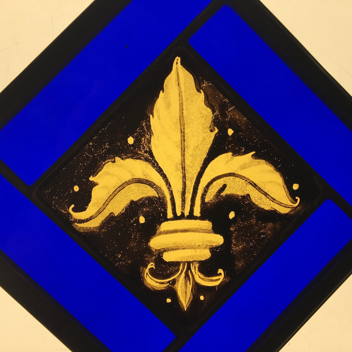 Gold fleur-de-lis stained glass design on a blue and black background