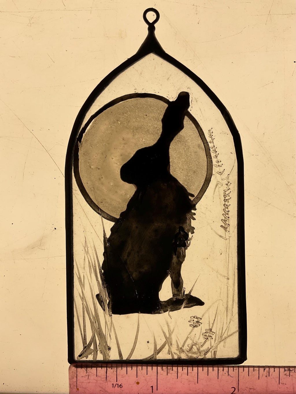 Silhouette of a hare or jack rabbit framed by  a full  moon  painted on a decorative arch on a light box with a ruler for scale.