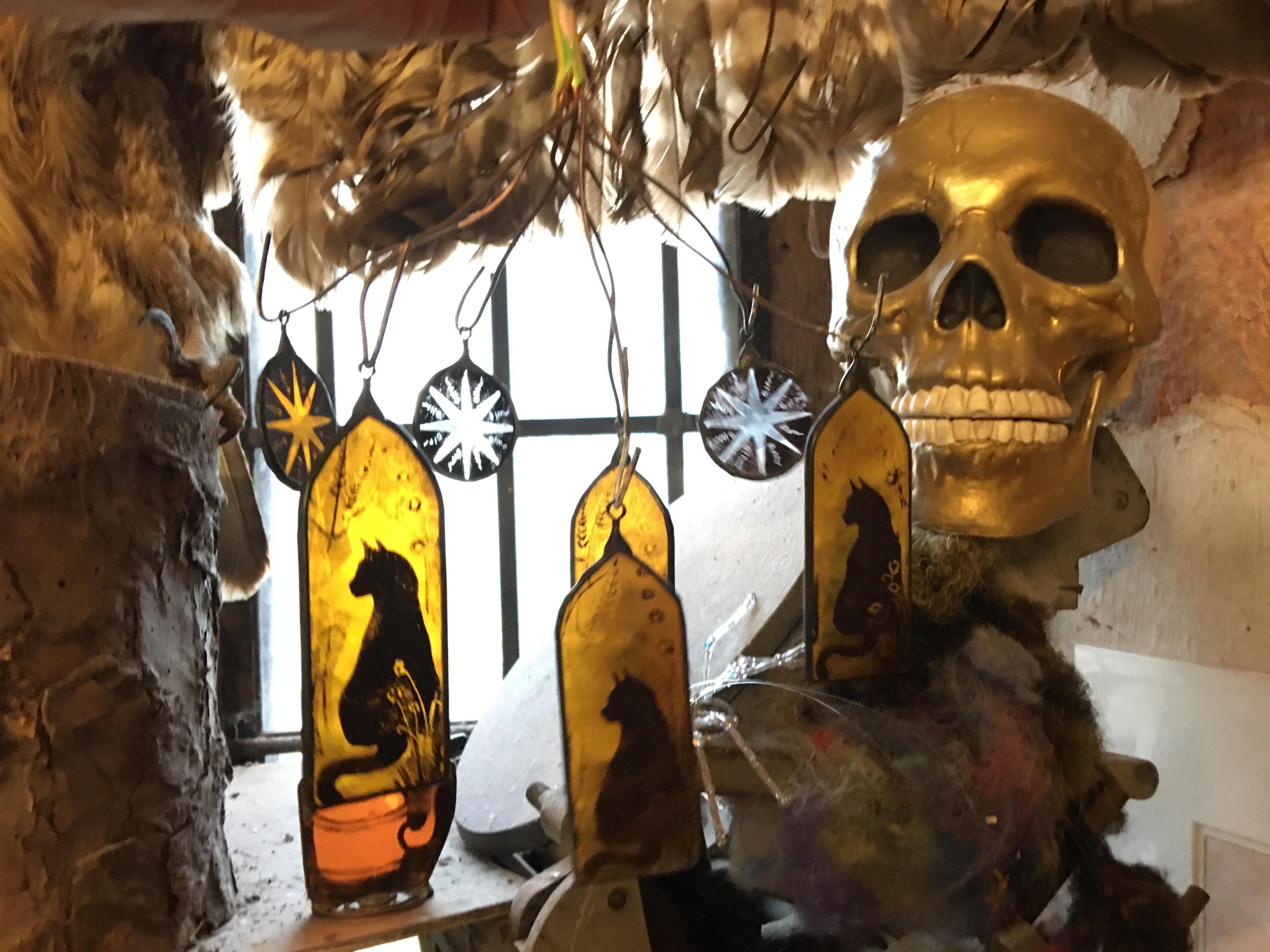 Decorative items including a gold skull and stained glass arched decors with black cat silhouettes.