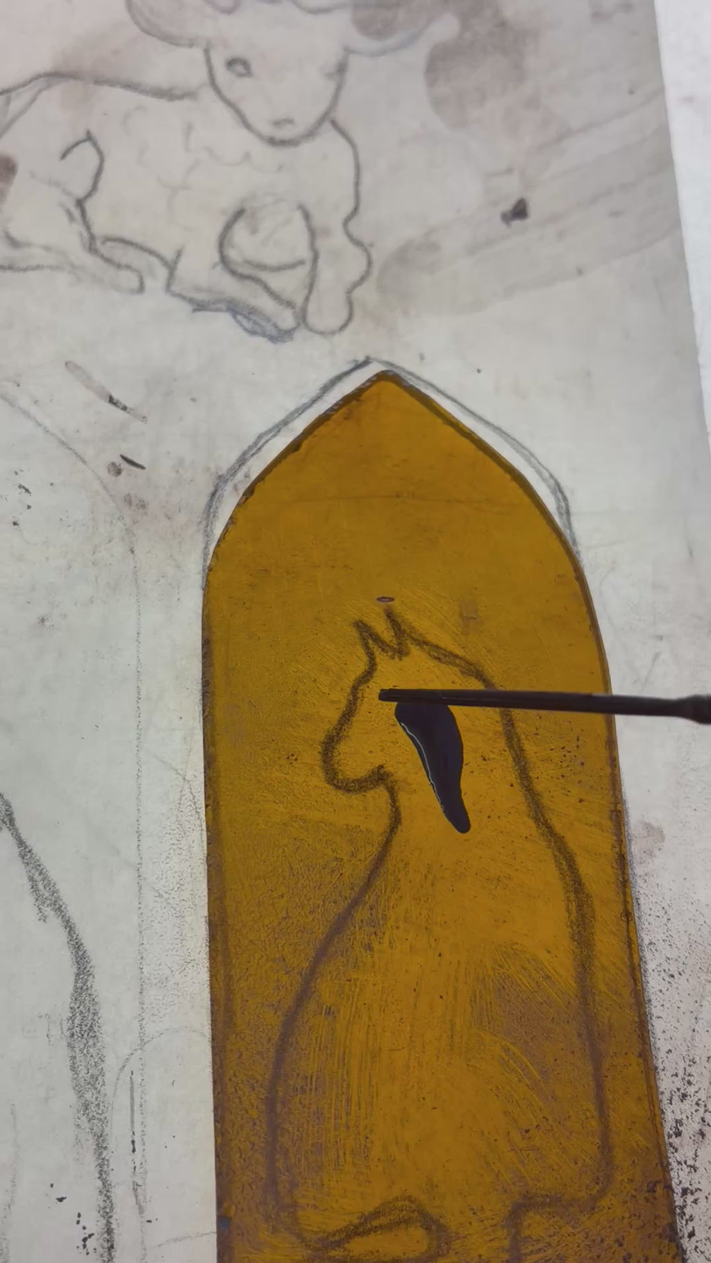 Brush painting the image of the cat on the amber glass.