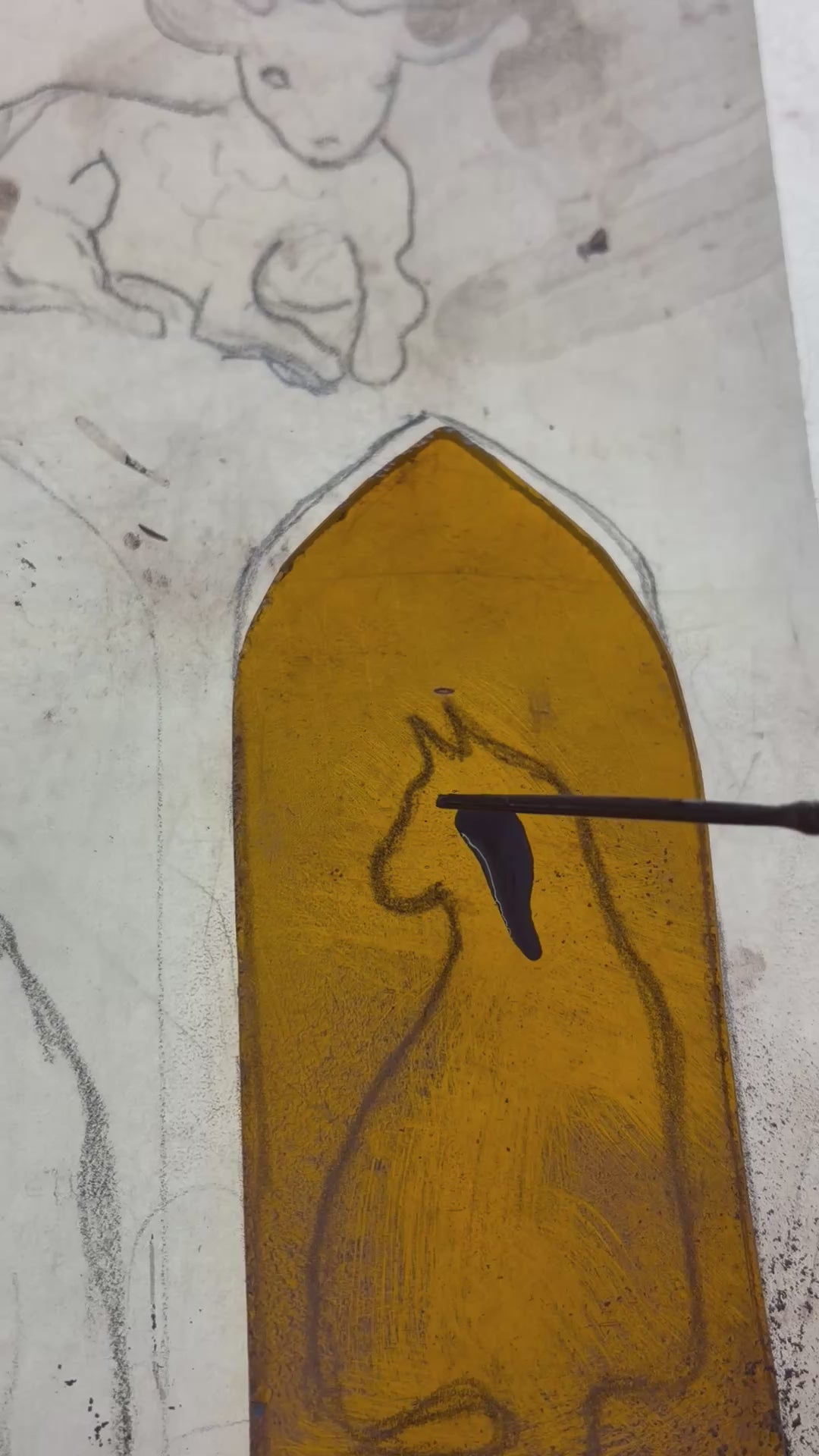 Brush painting the image of the cat on the amber glass.